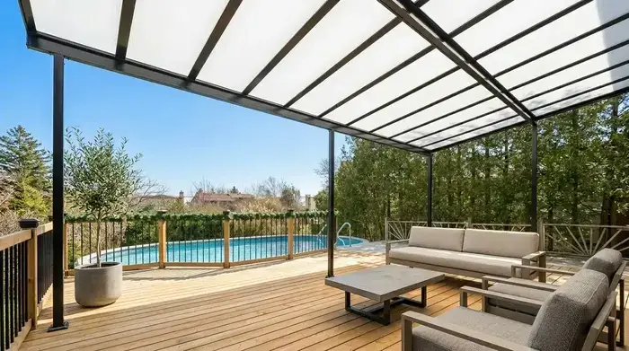 Black acrylic patio cover over a wooden deck with a pool view